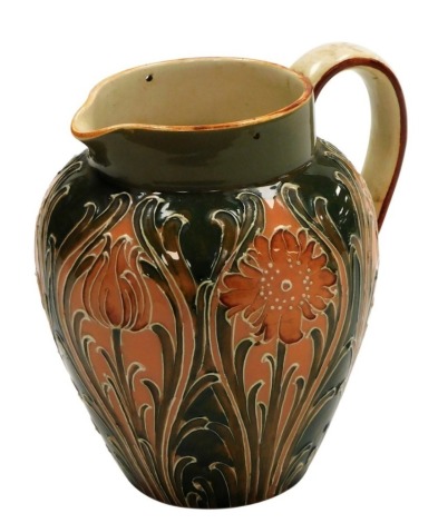 A Moorcroft Macintyre and Co Florian ware pottery jug, decorated with orange flowers and leaves against a green ground, lacking metal lid, 14cm high.