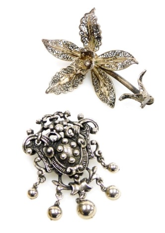 A Jewelcraft silver coloured metal costume brooch, modelled as a cartouche with pendant drops, and a filigree orchid shaped brooch. (2)