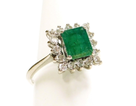 An emerald and diamond ring, the square cut emerald in a surround of sixteen brilliant cut diamonds, basket set in white metal, stamped 750, emerald approx 1ct, diamonds approx 0.5cts, ring size O½, 4.8g all in.