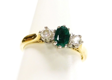 An 18ct gold emerald and diamond three stone dress ring, with central oval cut emerald in six claw setting, flanked by two round brilliant cut diamonds each in four claw setting, ring size N½, 4.1g all in, boxed.