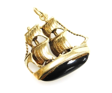 A 9ct gold ship pendant, the three masted ship with a black agate set base, 2cm wide, 6.3g all in.