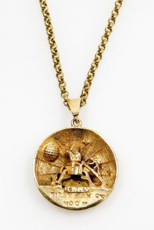 A 9ct gold First Man on The Moon pendant and chain, the circular pendant depicting moon scene and marked First Man on The Moon 10.7.69, with a 9ct gold curb link neck chain, the pendant 2.5cm high, the chain 44cm long, 13.7g all in.