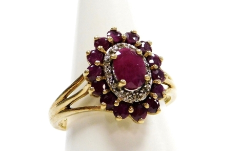 A 9ct gold ruby and diamond set dress ring, the oval ring head with central ruby, and further halo of tiny diamond and outer band of rubies with V splayed shoulders, misshapen, ring size O½, 4.3g all in.