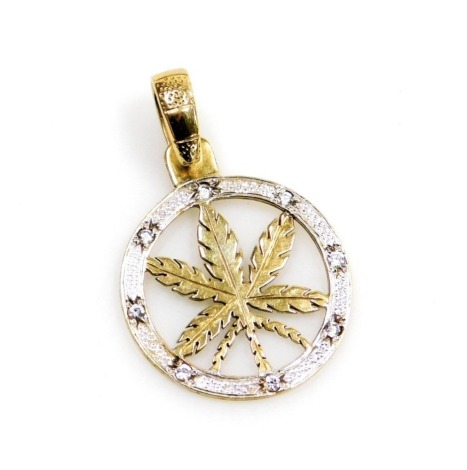 A 9ct gold Canadian maple leaf pendant, the circular pendant with a central Canadian maple leaf, surrounded by a white gold border set with tiny diamonds, with single pendant loop, 5cm high, 7.5g all in.