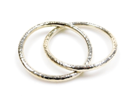 Two hammered silver bangles, makers stamp AB, intertwined, 7cm diameter, 44.8g all in.