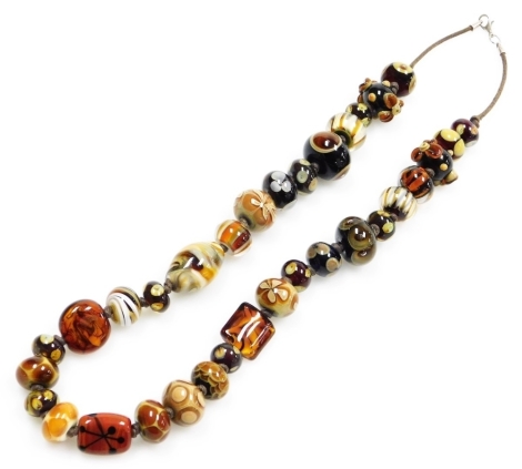 A modern Murano glass style beaded necklace, with various sized and shaped glass beads, some with raised relief on a brown string strand with white metal clasp stamped 925, 60cm long overall.