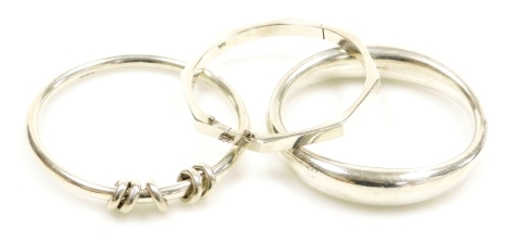 Three various bangles, comprising a silver octagonal bangle, 6cm diameter, a silver and five ring design bangle, 7cm diameter, and a curved white metal bangle, 7cm diameter, stamped 925 but weighted, 81.6g all in.