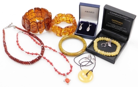 A group of assorted costume jewellery, comprising imitation amber bracelets, coral necklace, carved soapstone bangle, Happiness Honey jade bracelet, drop earrings, etc. (a quantity)