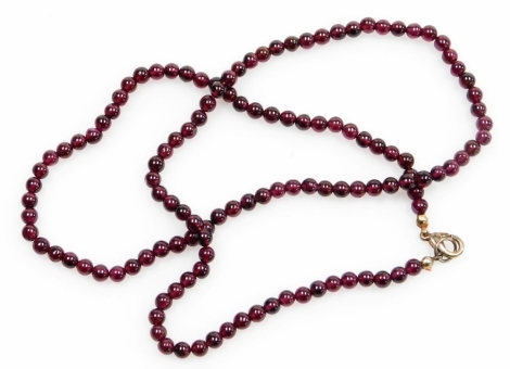 A garnet necklace, with small polished garnet beads, on rope string strand, with a plated clasp, 58cm long overall, 31.7g all in.