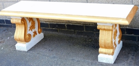 A composition stone garden bench, of rectangular form, with a moulded edge on shaped end supports, later painted gilt and white, 43cm high, 126cm wide.