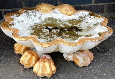 A composition bird bath, of shell form on paw feet, later painted in white and gilt, 56cm wide.