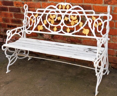 A cast iron garden bench, decorated with stylised branches, leaves and grapes, with a slatted seat, later painted white and gilt, 117cm wide.