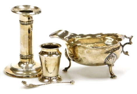 A group of small silver, comprising a Victorian cream jug, with a wavy border raised on three feet, hallmarks rubbed (handle AF), an Edward VII squat candlestick, base loaded, Birmingham 1901, 9cm high, and an urn shaped silver mustard pot, weight loaded,