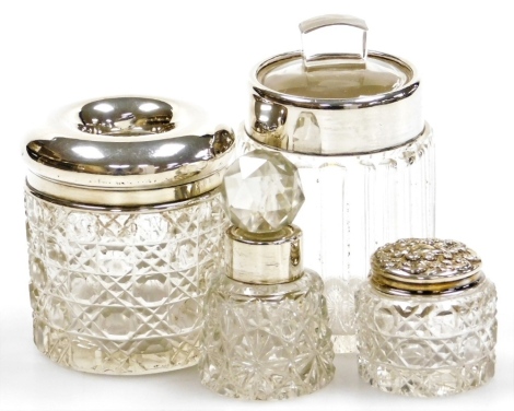 A group of cut glass and silver mounted dressing table bottles, to include a small scent bottle with a silver collar, Birmingham 1900, 7cm high, and a rouge pot with a repousse decorated lid, Birmingham 1900, etc. (4)