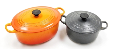 A Le Creuset cast iron and orange enamelled oval two handled casserole dish and cover, 32cm wide, and another similar smaller grey example, 24cm wide.