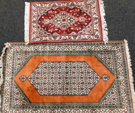 A Persian type rug, decorated with a pearl medallion, on an orange ground with multiple borders and spandrels, (AF), and a small Persian style rug. (2)