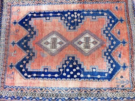 A Turkish rug, decorated with central lozenge in blue, on an orange ground with multiple borders, 208cm x 159cm.