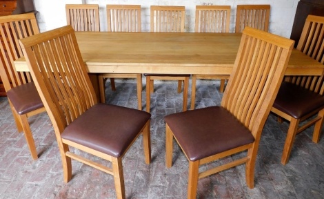 A John Lewis oak dining table, on end supports and a set of ten chairs, each with slatted back and padded seat, the table 75cm high, 220cm long, 101cm deep.