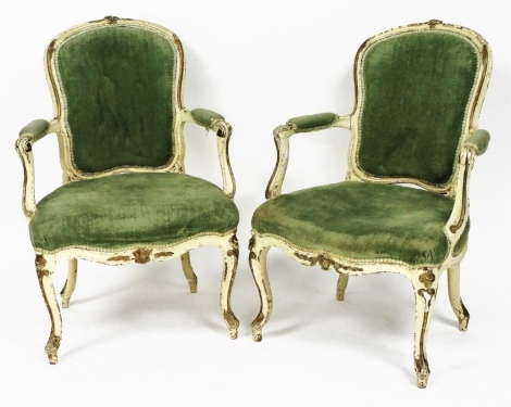 A pair of Victorian cream and parcel gilt fauteuil, in the French style, each with a green upholstered padded back armrest and seat, raised on cabriole legs.