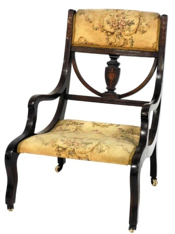 An Edwardian mahogany and marquetry inlaid nursing chair, with a padded back and seat, raised on sabre legs with ceramic castors.