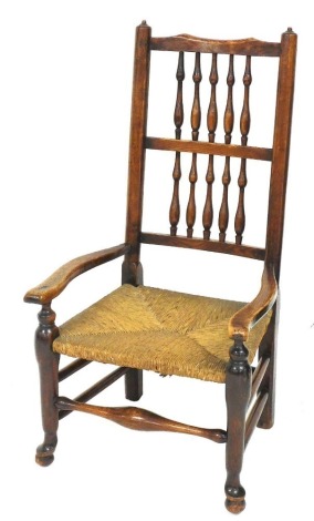 A Lancashire style oak chair, with double spindle back, low rush seat, shaped arms and front horizontal stretcher, 100cm high.