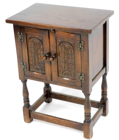 A Bevan Funnell Elizabethan style oak cupboard, with a pair of panelled carved cupboard doors, raised on turned supports united by a box stretcher, 68cm high, 50cm wide, 33cm deep.