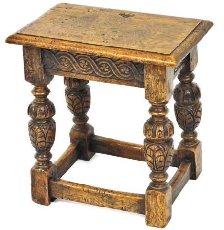 An oak joint stool in 17thC style, the rectangular top with a moulded edge, on carved cup and cover supports, with plain stretchers, 43cm wide.