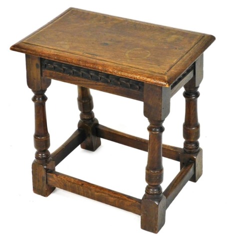 An oak joint stool in 17thC style, the rectangular top with a moulded edge, above a carved frieze on part turned supports, with plain stretcher, 43cm wide.