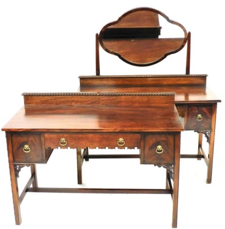 An Edwardian mahogany dressing table, with gadrooned galleried back, raised above frieze drawer flanked by cupboards, on square legs, joined by a H stretcher, 83cm high, 120cm wide, 54cm deep. and a mirror back dressing table, similarly modelled, with a s