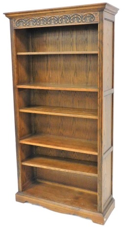 An Old Charm oak open bookcase, the top with a moulded cornice above a carved panel, with various shelves, 184cm high, 93cm wide, 35cm deep.