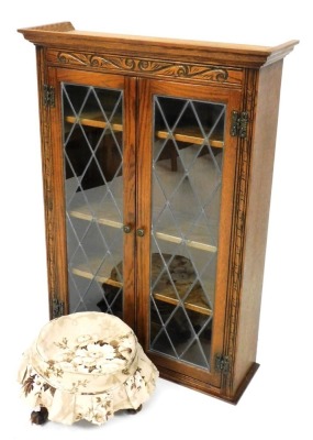 An oak Old Charm display cabinet, the top with a moulded cornice, with carved top, and two leaded glazed doors, 110cm high, and a 19thC walnut footstool, raised on three scroll cast legs, 36cm diameter,