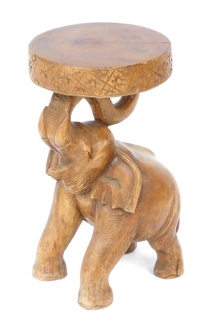 An Eastern hardwood carved elephant table, the circular drum top with floral detailing, held by an elephant, 50cm high.