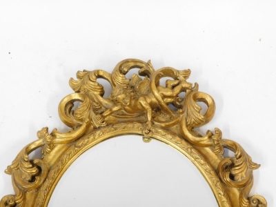 An early 20thC gilt gesso wall mirror, with rococo scrolled outer detailing and intertwined cherub figure, with an oval panel, later backed, 88cm high, 59cm wide. - 3