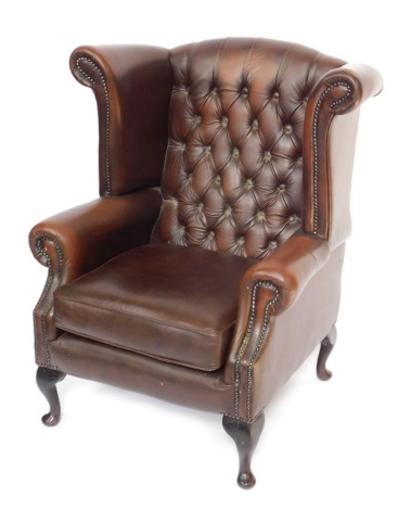 A brown leather Thomas Llyod Chesterfield wingback armchair, with button and stud detailing on mahogany out splayed legs, 102cm high, 76cm wide, 65cm deep.