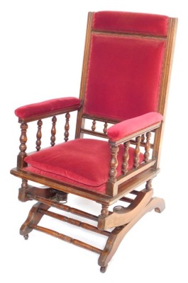 An early 20thC American walnut and upholstered rocking chair, with red upholstery, 113cm high, 55cm wide, 66cm deep.