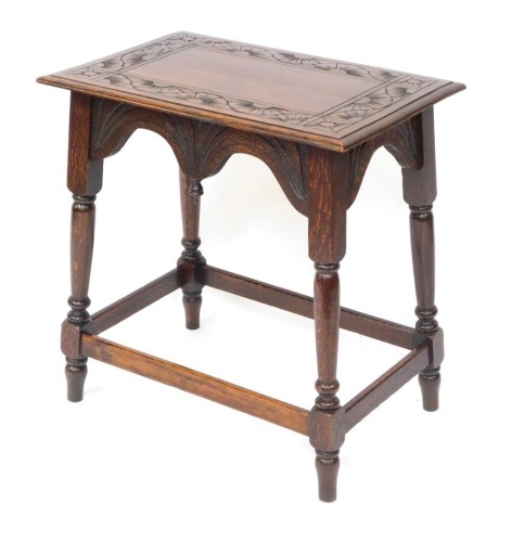 An early 20thC carved oak side table, the rectangular top of star and sun detailing, on a rectangular framed base, 64cm high, 61cm wide, 40cm deep.