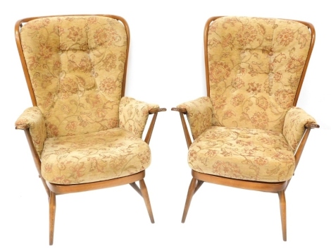 A pair of Ercol style upholstered wingback armchairs, each with a light elm finish and applied and buttoned floral upholstery, 110cm high, 50cm wide, 67cm deep. The upholstery in this lot does not comply with the 1988 (Fire & Fire Furnishing) Regulations,