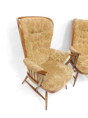 A pair of Ercol style upholstered wingback armchairs, each with a light elm finish and applied and buttoned floral upholstery, 110cm high, 50cm wide, 67cm deep. The upholstery in this lot does not comply with the 1988 (Fire & Fire Furnishing) Regulations, - 2