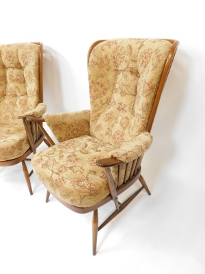 A pair of Ercol style upholstered wingback armchairs, each with a light elm finish and applied and buttoned floral upholstery, 110cm high, 50cm wide, 67cm deep. The upholstery in this lot does not comply with the 1988 (Fire & Fire Furnishing) Regulations, - 3