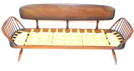 An Ercol dark elm sofa base, with shield back and stick design supports, terminating in castors, lacking cushions, 72cm high, 205cm wide, 48cm deep.