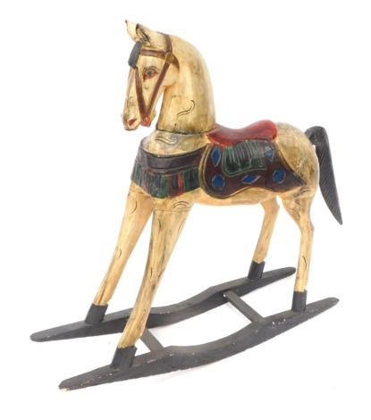 A painted pine rocking horse, with applied red saddle in Eastern design, on a blackened base, 95cm high, 85cm wide, 23cm deep.