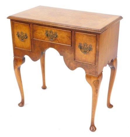 A Georgian style walnut lowboy, with one short and two deep drawers above a shaped apron, raised on shell carved cabriole legs, 59cm high, 74cm wide, 41cm deep.