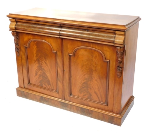 A Victorian flame mahogany side cabinet, with two cushion drawers, over a pair of panelled doors, flanked by foliate carving, raised on a plinth base, 98cm high, 127cm wide, 48cm deep.