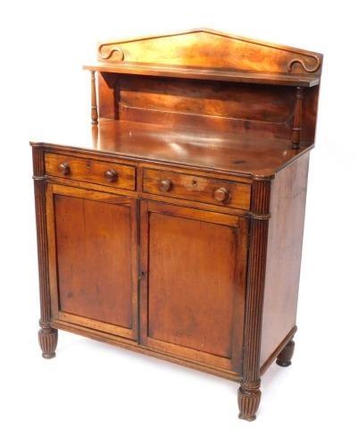 A late Regency mahogany chiffonier, the pendimented back with a single shelf raised on turned columns, over two drawers above a pair of panelled doors, raised on fluted columns and feet, 123cm high, 91cm wide, 48cm deep.