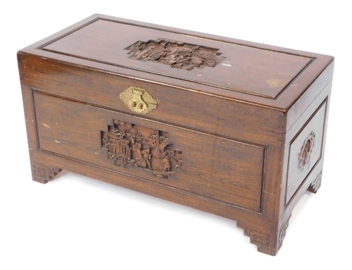 An early 20thC Chinese camphorwood chest, carved to the lid and front with landscapes and figures in bass relief, the sides with smaller carvings, raised on cruel carved bracket feet, 50cm high, 94cm wide, 46cm deep.