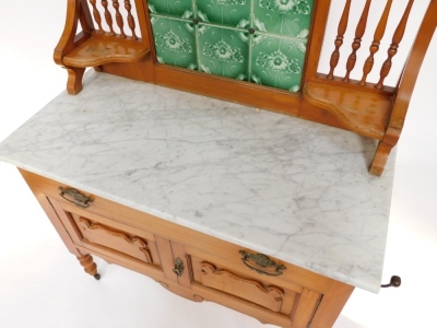 A Victorian washstand, with a leaf carved pediment over a six green tile floral splash back, flanked by spindles and shaped shelves, the marble top over a long drawer and panelled doors, raised on turned legs, on castors, 133cm high, 99cm wide, 46.5cm dee - 2