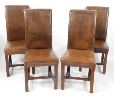 A set of four brown leather and oak framed dining chairs.