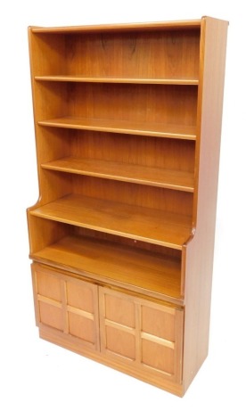 A Nathan teak bookcase, with five shelves, over a pair of panelled cupboard doors, enclosing a further shelf, raised on a plinth base, 57.5cm high, 84cm wide, 34cm deep.
