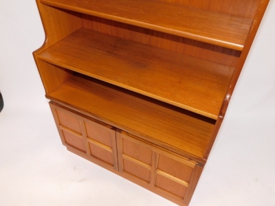 A Nathan teak bookcase, with five shelves, over a pair of panelled cupboard doors, enclosing a further shelf, raised on a plinth base, 57.5cm high, 84cm wide, 34cm deep. - 2