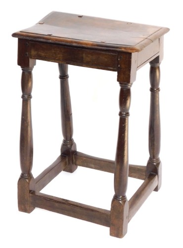 An 18thC oak joint stool, raised on turned legs united by a box stretcher, 64cm high.